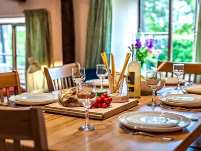 a wooden table with plates and wine glasses on it at 4 Bed in Hereford oc-86497 in Llanveynoe