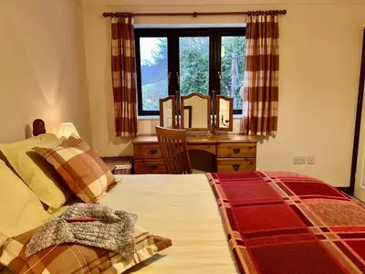 a bedroom with a bed and a desk and a window at Caer Dderwen Oak Field family home in Dolgellau in Dolgellau