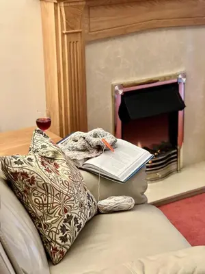 a book on the back of a couch with a glass of wine at Caer Dderwen Oak Field family home in Dolgellau in Dolgellau