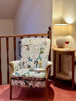 a chair sitting next to a table with a glass of wine at Caer Dderwen Oak Field family home in Dolgellau in Dolgellau