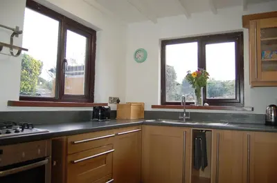 a kitchen with a sink and two windows at Idris View Family Holiday Home in Tywyn