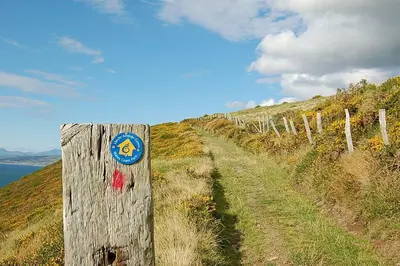 a wooden fence on a hill with a sign on it at Idris View Family Holiday Home in Tywyn