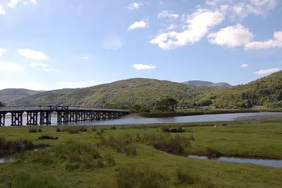 a bridge over a river with mountains in the background at Glan yr Afon in Dolgellau in Dolgellau