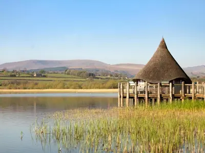 a hut with a thatched roof on a lake at 3 Bed in Brecon oc-88249 in Brecon