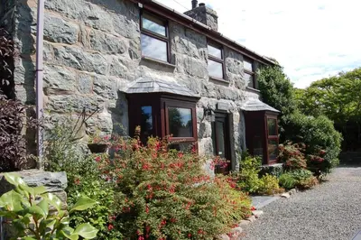 a stone house with a bunch of flowers in front of it at Henborth Mawr Cottage in Talybont in Talybont