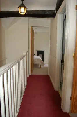 a hallway with a red carpet and a room with a bed at Henborth Mawr Cottage in Talybont in Talybont