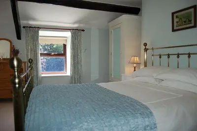 a bedroom with a large bed and a window at Henborth Mawr Cottage in Talybont in Talybont