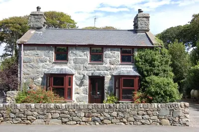 an old stone house with a stone wall at Henborth Mawr Cottage in Talybont in Talybont