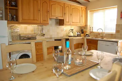 a kitchen with a wooden table with wine glasses on it at Glyn Saron near Tywyn in Bryn-crug