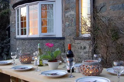 a wooden table with wine bottles and glasses on it at Minafon near Barmouth in Llanaber