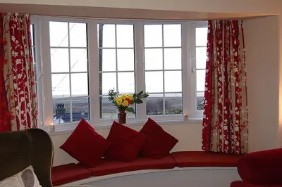 a living room with a red couch in front of windows at Minafon near Barmouth in Llanaber