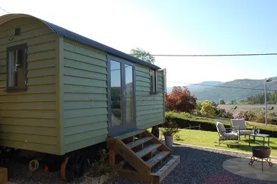 a green tiny house sitting on top of a patio at Paradwys in Dolgellau in Dolgellau
