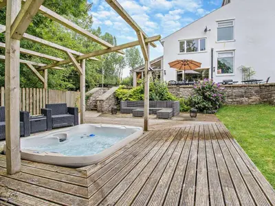 a hot tub on a wooden deck in front of a house at 6 Bed in Brecon oc-bn171 in Llanspyddid