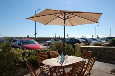 a table with an umbrella in a parking lot at Sand Dune Apartment in Barmouth in Barmouth