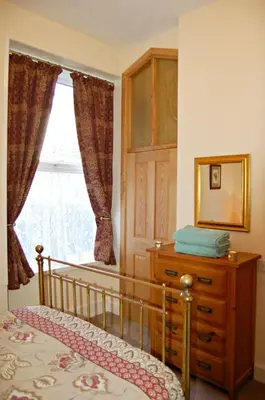 a bedroom with a bed and a dresser and a window at Sand Dune Apartment in Barmouth in Barmouth