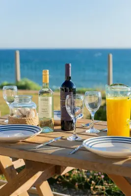 a wooden picnic table with wine bottles and glasses at Sound of the Sea, beach front Bungalow with hot tub, in Tywyn in Tywyn