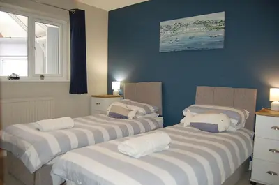 two beds in a room with blue walls at Sound of the Sea, beach front Bungalow with hot tub, in Tywyn in Tywyn