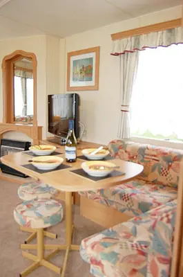 a living room with a table and a couch at Caravan 309 Bryn Y Mor Beach Side Park in Tywyn