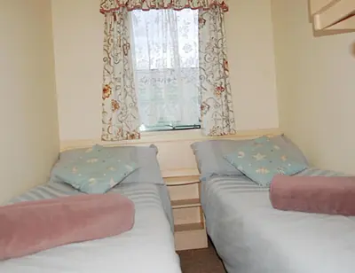 two beds in a room with a window at Caravan 309 Bryn Y Mor Beach Side Park in Tywyn