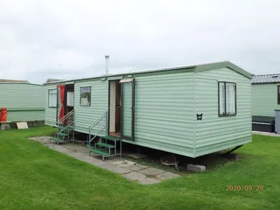 a green mobile home with stairs in a yard at Caravan 309 Bryn Y Mor Beach Side Park in Tywyn