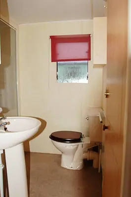 a bathroom with a toilet and a sink and a red window at Caravan 309 Bryn Y Mor Beach Side Park in Tywyn