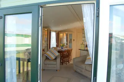 a living room and dining room with a sliding glass door at Caravan 251 Bryn Y Mor Beach Side Park in Tywyn