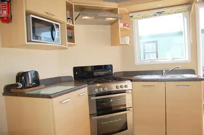a small kitchen with a stove and a sink at Caravan 251 Bryn Y Mor Beach Side Park in Tywyn