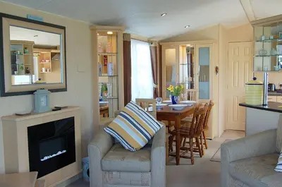 a living room with a fireplace and a table and chairs at Caravan 251 Bryn Y Mor Beach Side Park in Tywyn