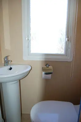 a bathroom with a sink and a toilet and a window at Caravan 251 Bryn Y Mor Beach Side Park in Tywyn