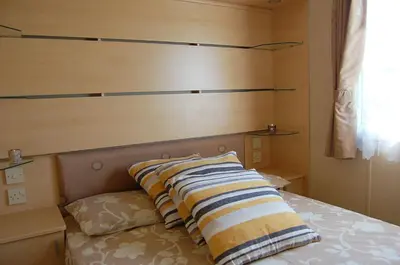 a bedroom with a bed with pillows on it at Caravan 251 Bryn Y Mor Beach Side Park in Tywyn