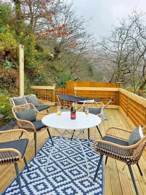 a patio with a table and chairs on a wooden deck at South View Cottage with Terrace and Coastal Views in Fairbourne