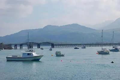 a group of boats in the water near a bridge at South View Cottage with Terrace and Coastal Views in Fairbourne