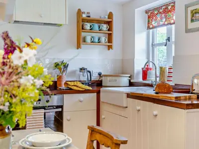a kitchen with white cabinets and a table with flowers at 1 Bed in Brecon oc-bn157 in Llangorse