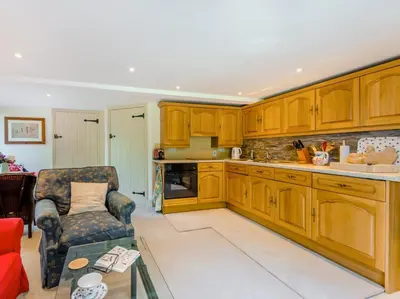 a kitchen with wooden cabinets and a chair at 1 Bed in Clyro BN290 in Clyro