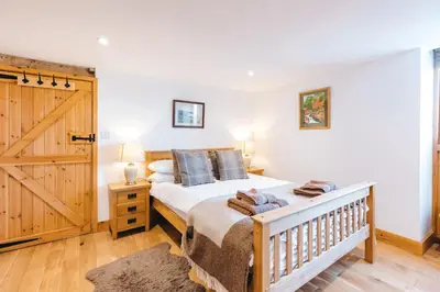 a bedroom with a bed and a wooden door at ryton grange hay barn sleeps 6 in Shrewsbury