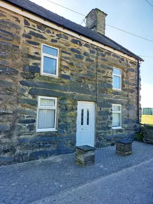 a stone house with a white door and windows at Craig View Fishermans Cottage nr Harbour and Beach in Barmouth