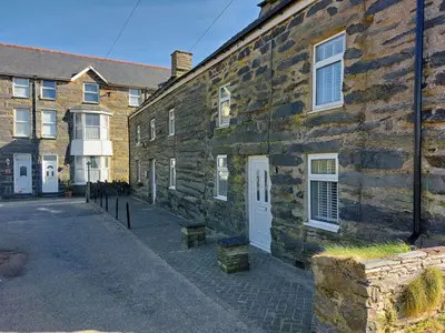 a stone building with a white door on a street at Craig View Fishermans Cottage nr Harbour and Beach in Barmouth