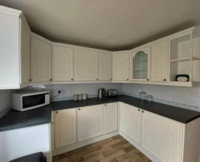 a white kitchen with white cabinets and a microwave at Craig View Fishermans Cottage nr Harbour and Beach in Barmouth