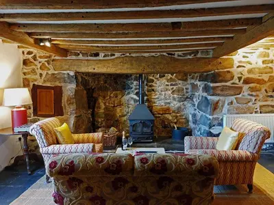 a living room with a couch and a stone fireplace at Gallestra a Rustic, Rural Retreat Farm House Nr Dolgellau Snowdonia in Dolgellau