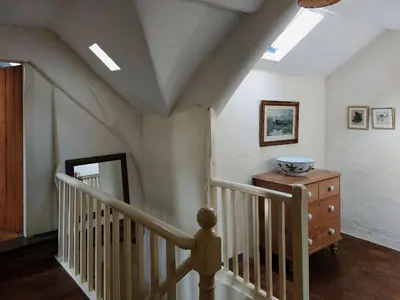 a room with a staircase with a mirror and a dresser at Gallestra a Rustic, Rural Retreat Farm House Nr Dolgellau Snowdonia in Dolgellau