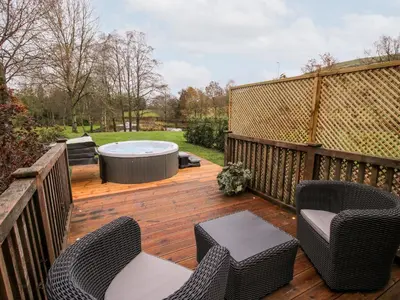 a wooden deck with chairs and a hot tub at Pultheley Cottage in Montgomery