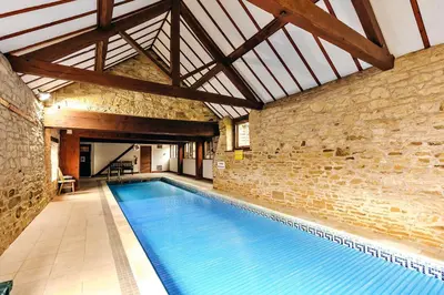a large swimming pool in a building with a brick wall at Finest Retreats - The Onibury in Onibury