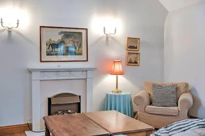 a living room with a fireplace and a chair and a table at Finest Retreats - The Onibury in Onibury