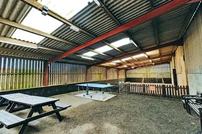 a ping pong table and benches in a barn at Finest Retreats - The Onibury in Onibury