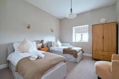 a bedroom with two beds and a chair in it at Finest Retreats - The Park in Onibury