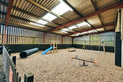 a barn with a playground with swings and a slide at Finest Retreats - Norton Cottage in Onibury