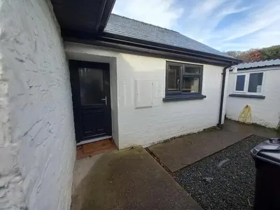 a small white house with a black door at Penglais Lodge in Aberystwyth