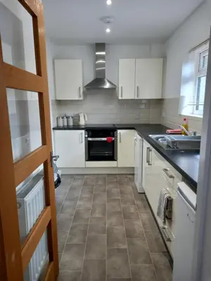 a kitchen with white cabinets and a tile floor at Penglais Lodge in Aberystwyth