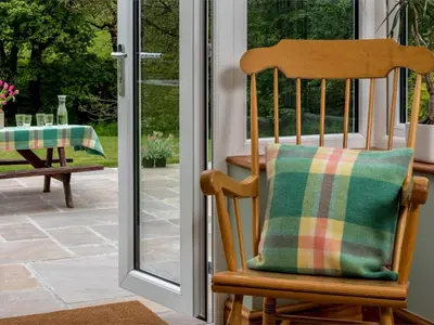 a wooden rocking chair with a plaid pillow on a porch at 4 Bed in Brecon oc-bn151 in Devynock