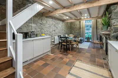a kitchen and dining room with a stone wall at Cheerful 2 bedroom cottage with garden in Llanelltyd